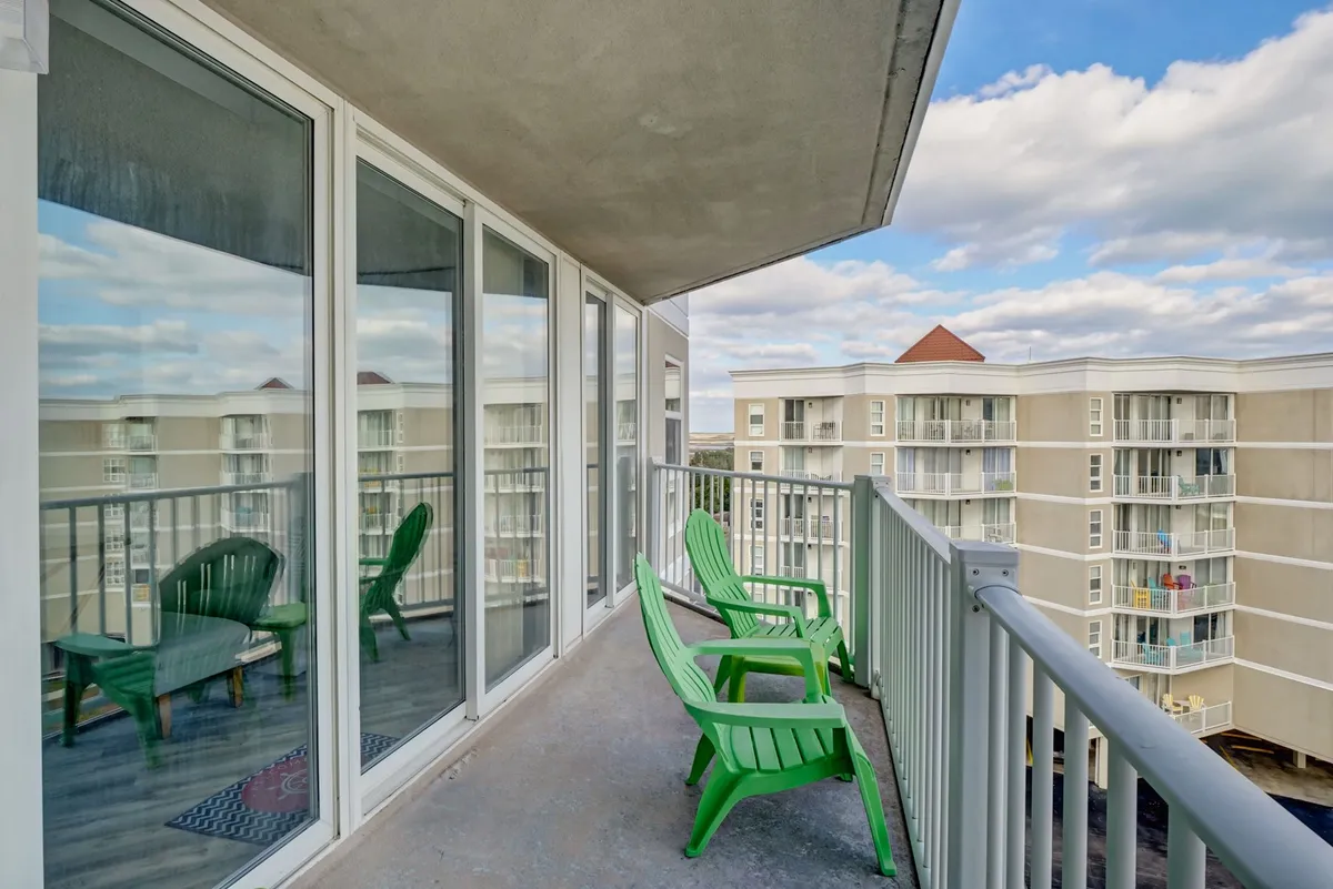 This image showcases a private balcony with green chairs, offering a sweeping view of the ocean through the glass railing. The tranquil setting is perfect for enjoying morning coffee or cocktails at sunset, embodying the romantic and serene atmosphere described in the section.